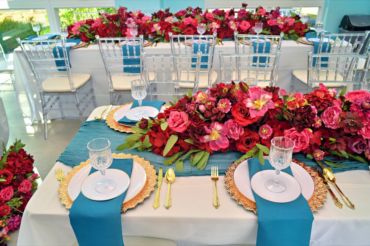 Reception table setting with teal linens and florals